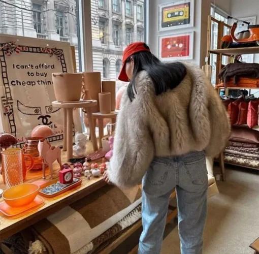 femme de dos dans une boutique qui porte le Blouson fausse fourrure gris